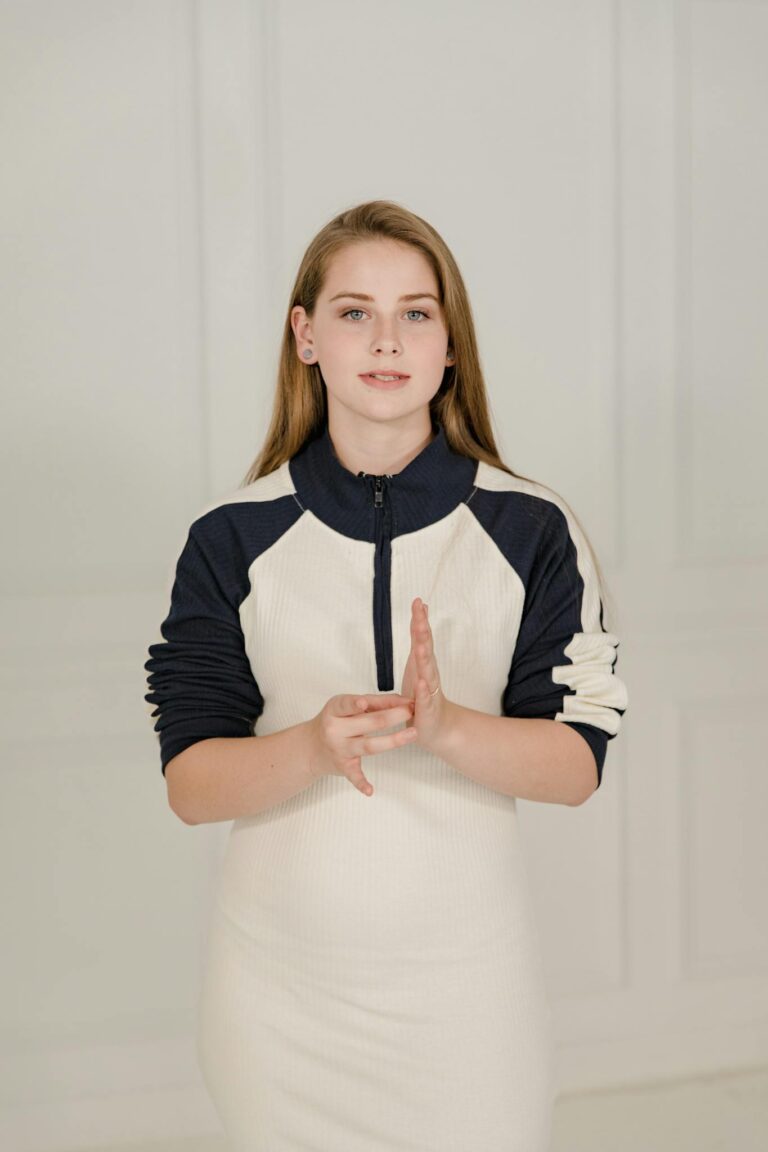 A woman using sign language to communicate, standing indoors, signifying inclusivity and communication.