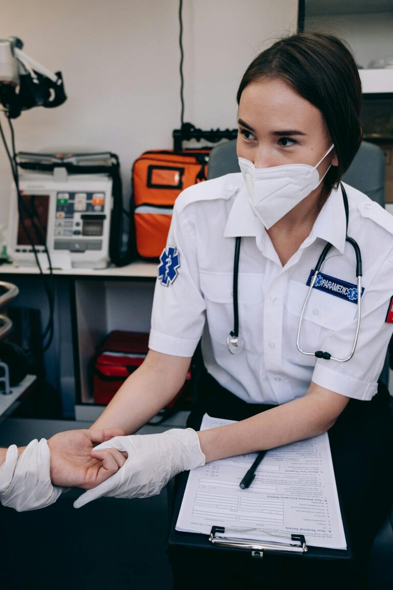 Paramedic using stethoscope while checking pulse of a patient in a clinic setting.